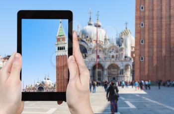 travel concept - tourist photographs campanile of St Mark's Cathedral on square Piazza San Marco in Venice city in Italy in spring on tablet