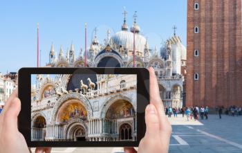 travel concept - tourist photographs St Mark's Basilica on square Piazza San Marco in Venice city in Italy in spring on tablet