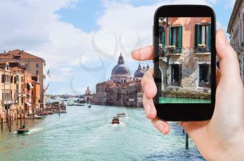 travel concept - tourist photographs urban house on waterfront of grand canal in Venice city in Italy in spring on smartphone