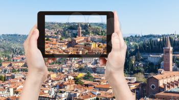travel concept - tourist photographs Verona town with Sant' Anastasia Church in Italy from tower Torre dei Lamberti in spring on tablet