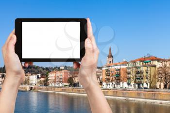 travel concept - tourist photographs waterfront in Verona city in sunny spring day on tablet with cut out screen for advertising logo