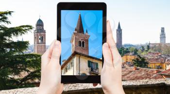 travel concept - tourist photographs towers of Verona city in Italy in spring on tablet