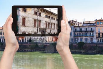 travel concept - tourist photographs houses on waterfronts in Verona city in Italy in spring on tablet