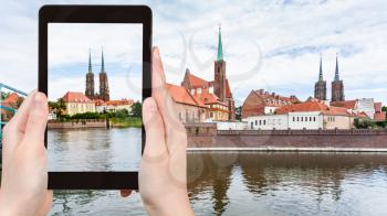travel concept - tourist photographs Cathedral on Tumski island in Wroclaw city from Oder river on smartphone
