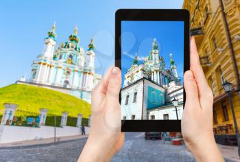 travel concept - tourist photographs St Andrew's Church from Andriyivskyy Descent in Kiev city in Ukraine on tablet