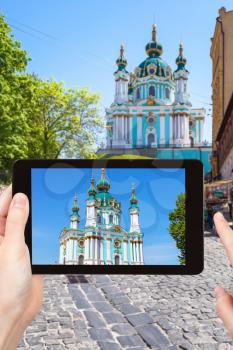 travel concept - tourist photographs St Andrew's Church on Andriyivskyy Descent street in Kiev city in Ukraine on tablet