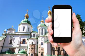 travel concept - tourist photographs Saint Sophia (Holy Sophia, Hagia Sophia) Cathedral in Kiev city in Ukraine on smartphone with cut out screen for advertising logo