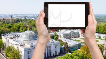 travel concept - tourist photographs Verkhovna Rada building (Supreme Council of Ukraine) and Mariyinsky palace in Mariinsky park in Kiev city on tablet with cut out screen for advertising logo