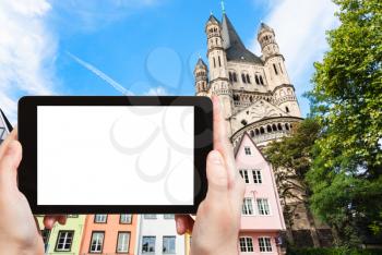 travel concept - tourist photographs medieval houses on Fischmarkt area and Great St Martin Church in Cologne city in Germany in september on tablet with cut out screen for advertising logo