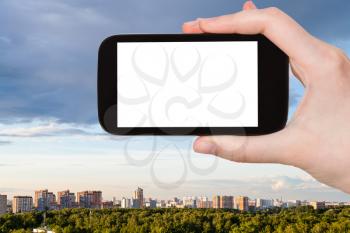 travel concept - tourist photographs modern skyline with green park in Moscow city in Russia in summer evening on smartphone with cut out screen for advertising logo