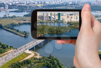 travel concept - tourist photographs modern living district Pavshinskaya Poyma in Krasnogorsk town on waterfront of Picturesque Bay of Moskva River in Moscow suburb in Russia on smartphone