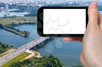 travel concept - tourist photographs Novorizhskoye Shosse of Russian route M9 Baltic Highway over Moskva river in Pavshinsky Floodplain near Moscow city on smartphone with cut out screen