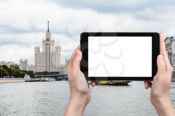 travel concept - tourist photographs Kotelnicheskaya Embankment High-Rise Building and Moskva River in Moscow in autumn on tablet with cut out screen for advertising