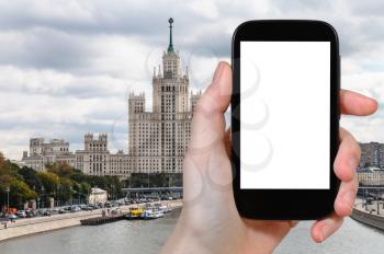 travel concept - tourist photographs Kotelnicheskaya Embankment High-Rise Building and Bolshoy Ustinsky Bridge of Moskva River in Moscow in autumn on smartphone with cut out screen for advertising