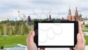 travel concept - tourist photographs Zaryadye park and view of Kremlin Towers and Cathedrals in Moscow city in autumn on tablet with cut out screen for advertising logo