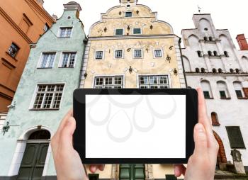 travel concept - tourist photographs Three Brothers, early Renaissance style houses, on Maza Pils iela in Old Riga Town Latvia in autumn on tablet with cut out screen for advertising logo