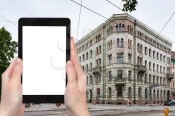 travel concept - tourist photographs apartment house on Krisjana Valdemara iela street in Old Riga Town Latvia in autumn on tablet with cut out screen for advertising logo