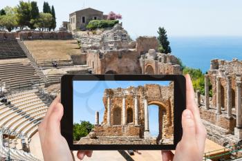 travel concept - tourist photographs Teatro antico di Taormina, ancient Greek Theater (Teatro Greco) in Taormina city in Sicily Italy in summer on tablet