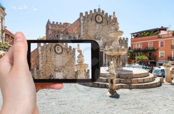 travel concept - tourist photographs Piazza Del Duomo and Duomo di Taormina (Cathedral San Nicolo di Bari) in Taormina city in Sicily Italy in summer on smartphone