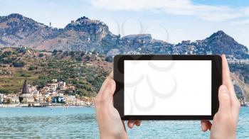 travel concept - tourist photographs Giardini-Naxos town and Taormina city on cape in Sicily Italy in summer season on tablet with cut out screen for advertising logo