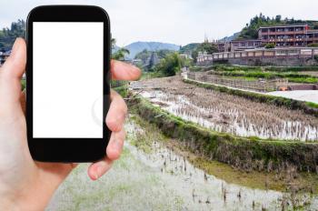 travel concept - tourist photographs terraced rice fields in Chengyang village of Sanjiang Dong Autonomous County in China in spring on tablet with cut out screen for advertising logo