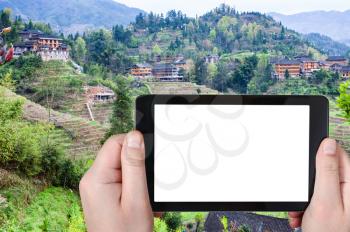 travel concept - tourist photographs Dazhai village with Rice Terraces in Longsheng (Dragon's Backbone, Longji) county in China in spring season on smartphone with cut out screen for advertising logo