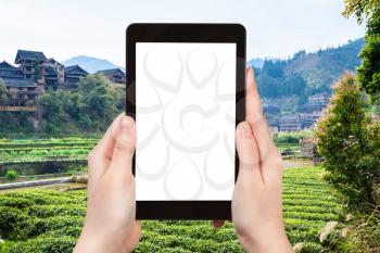 travel concept - tourist photographs tea fields in Chengyang village of Sanjiang Dong Autonomous County in China in spring on tablet with cut out screen for advertising