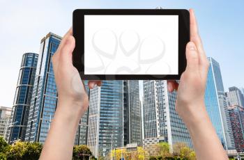 travel concept - tourist photograps high-rise buildings in Zhujiang district of Guangzhou city in China in spring on tablet with cut out screen for advertising logo