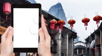 travel concept - tourist photograps street in Xing Ping town in Yangshuo county in China in spring on tablet with cut out screen for advertising logo