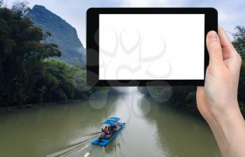 travel concept - tourist photograps boat on river in Yangshuo county in China in spring morning on smartphone with cut out screen for advertising logo
