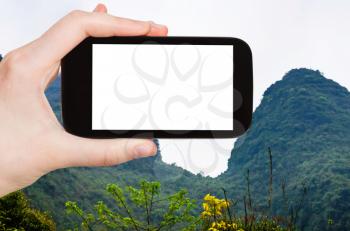 travel concept - tourist photograps green karst peaks in Yangshuo County in China in spring season on smartphone with cut out screen for advertising logo