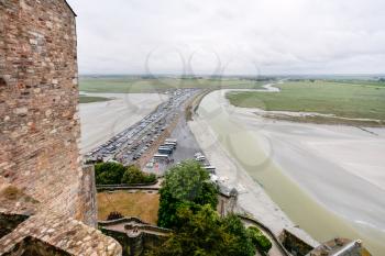Travel to France - above view of car parking and the causeway to Le Mont Saint-Michel island in Normandy in rain