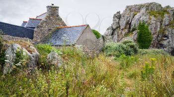 travel in France - traditional Breton stone house and rocks in Plougrescant town of the Cotes-d'Armor department in Brittany in rainy summer day