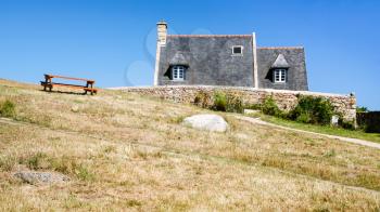 travel to France - bench on hill near country houses in Brehat commune on Ile-de-Brehat island in Cotes-d'Armor department of Brittany in summer sunny day