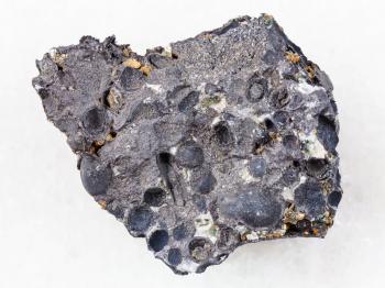 macro shooting of natural mineral rock specimen - raw pisolite stone from magnetite and hematite ore on white marble background from Korshunovskoe mine, Irkutsk region, Russia