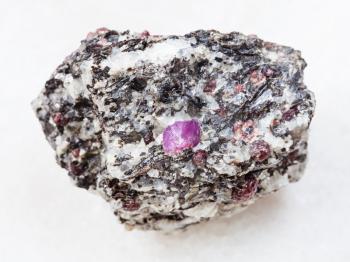 macro shooting of natural mineral rock specimen - raw corundum crystals in gneiss stone on white marble background from Hit-island of Upper Pulongskoye Lake, Karelia in Russia