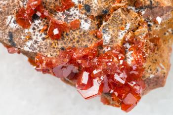 macro shooting of natural mineral rock specimen - rough crystals of Vanadinite stone close up on white marble background from Morocco