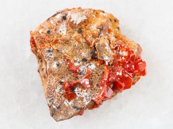 macro shooting of natural mineral rock specimen - raw crystals of Vanadinite on stone on white marble background from Morocco