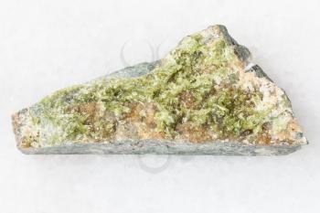 macro shooting of natural mineral rock specimen - rough crystal of green Vesuvianite gemstone on white marble background from Bazhenovskoe mine, Sverdlovsk region, Ural Montains, Russia