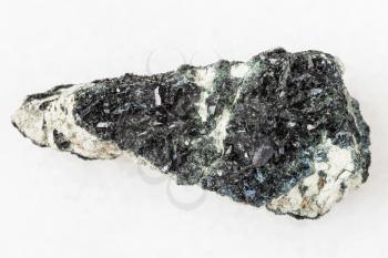 macro shooting of natural mineral stone specimen - raw crystal of hornblende on amphibole - carbonate rock on white marble background from Korshunovskoe mine of Irkutsk region of Russia