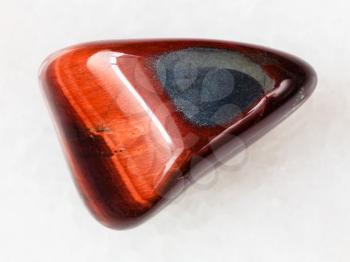 macro shooting of natural mineral rock specimen - tumbled Ox's eye gemstone on white marble background from South Africa