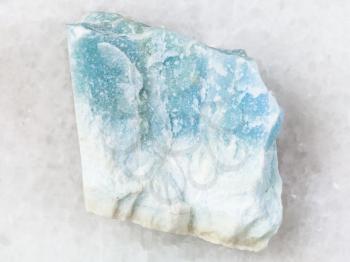macro shooting of natural mineral rock specimen - raw blue Violane stone on white marble background from Qurama Mountains in Uzbekistan