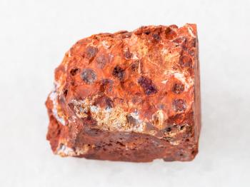 macro shooting of natural mineral rock specimen - raw red bauxite stone on white marble background