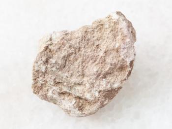 macro shooting of natural mineral rock specimen - rough marl stone on white marble background