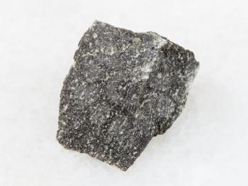 macro shooting of natural mineral rock specimen - piece of Andesite stone on white marble background