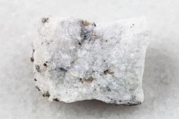 macro shooting of natural mineral rock specimen - raw carbonatite stone on white marble background