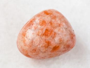 macro shooting of natural mineral rock specimen - polished sunstone (heliolite) gem stone on white marble background from USA