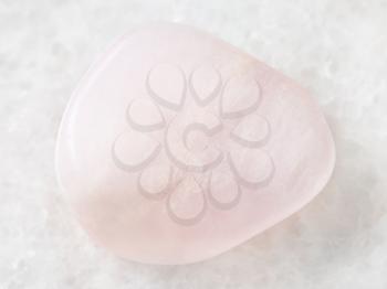 macro shooting of natural mineral rock specimen - polished pink petalite gemstone on white marble background