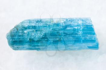 macro shooting of natural mineral rock specimen - rough crystal of aquamarine (blue beryl) gemstone on white marble background from Sherlova Gora (Sherlovaya Gora) mine, Transbaikalia, Russia