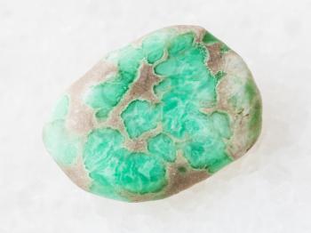macro shooting of natural mineral rock specimen - tumbled Variscite gemstone on white marble background from Utah, USA